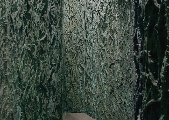 Installation image of tall green panels with a bark-like texture.