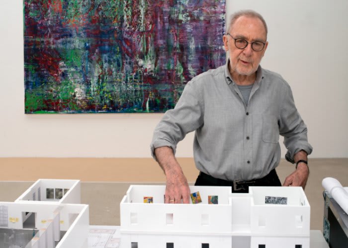Portrait of Gerhard Richter standing in front of a large abstract painting.