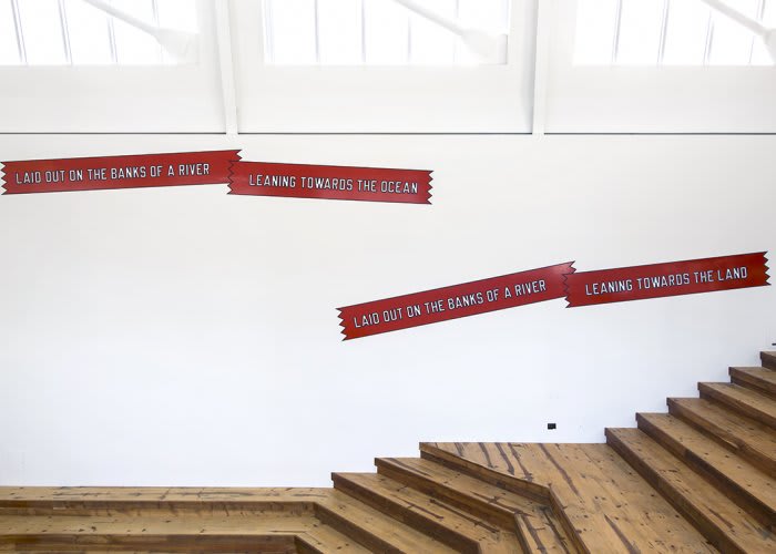 Installation image of a staircase with text on red highlight placed on the adjacent wall.