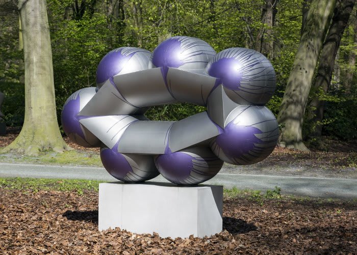 Metal oval shaped sculpture installed in nature. Seven silver circles with purple drip paint morph into the sculpture