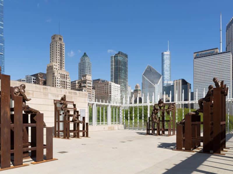 Structural stair-like metal sculptures sit on a roof overlooking a skyline.