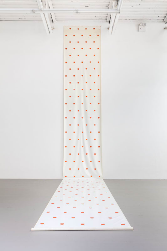 Installation view of a long painting of equidistant square red brushstrokes on a white background, unrolled from the top of the gallery wall onto the floor.