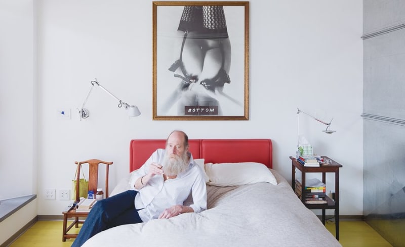 Image of aritst Lawrence Weiner leaning against bed.