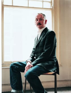 Photo portrait of person on chair in front of bright window.