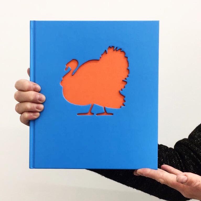 A catalog of a blue book with a silhouette of a red turkey in the center.
