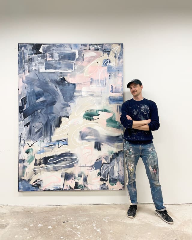 artist marcus aitken standing next to a large abstract painting which uses raw canvas blue pink white and cream colours freedom of movement and expression