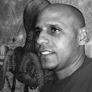 Black and white photograph of a man with a light goatee looking off to the left. He has a bald head. 