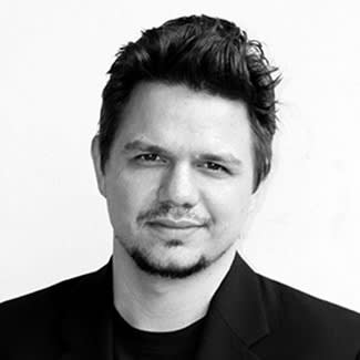 Black and white photograph of a man with light skin and a goatee. He looks at the camera.