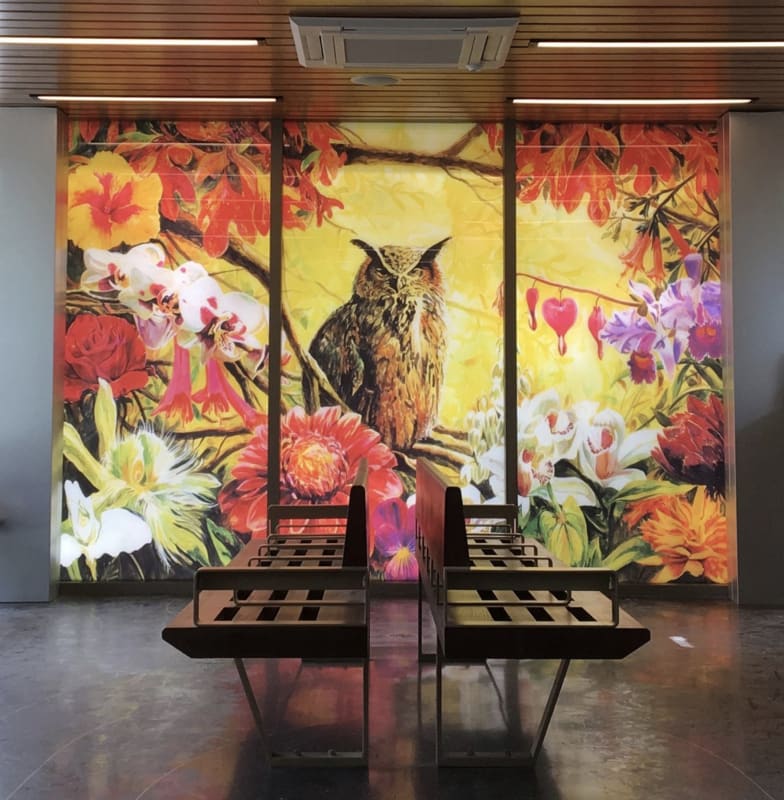 Photograph of two benches in front of a stain-glass mural of an owl and flowers
