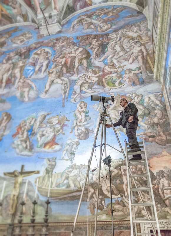 Photographer standing on a ladder taking photographs of the Sistine Chapel for the new publication