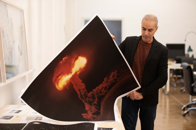 Francesco Jodice in his studio holding a print of an explosion.