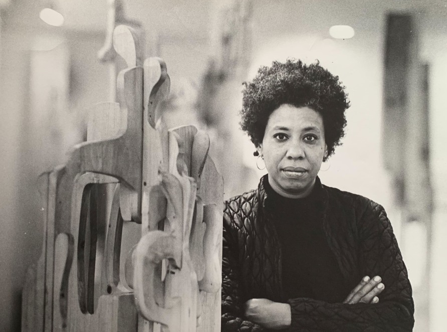 <span class="artist"><strong>Mildred Thompson</strong></span>, <span class="title"><em>artist with a free-standing wood assemblage</em></span>
