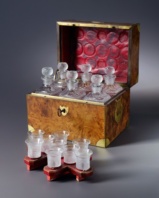 An Empire tantalus with six bottles and 9 glasses