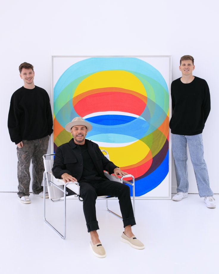 Square One Gallery owners Max Berman, Tanner Steslow, and Ted Collier in front of an original painting by Ted Collier