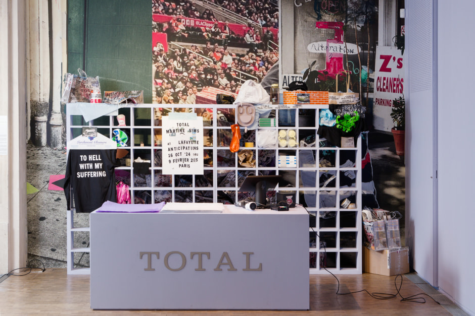 Total, 2024  desk, cashier, till, shelving unit, miscellaneous items, clothing, hat, shoes, water bottles, shopping bags, card machine, scanning device  dimensions variable