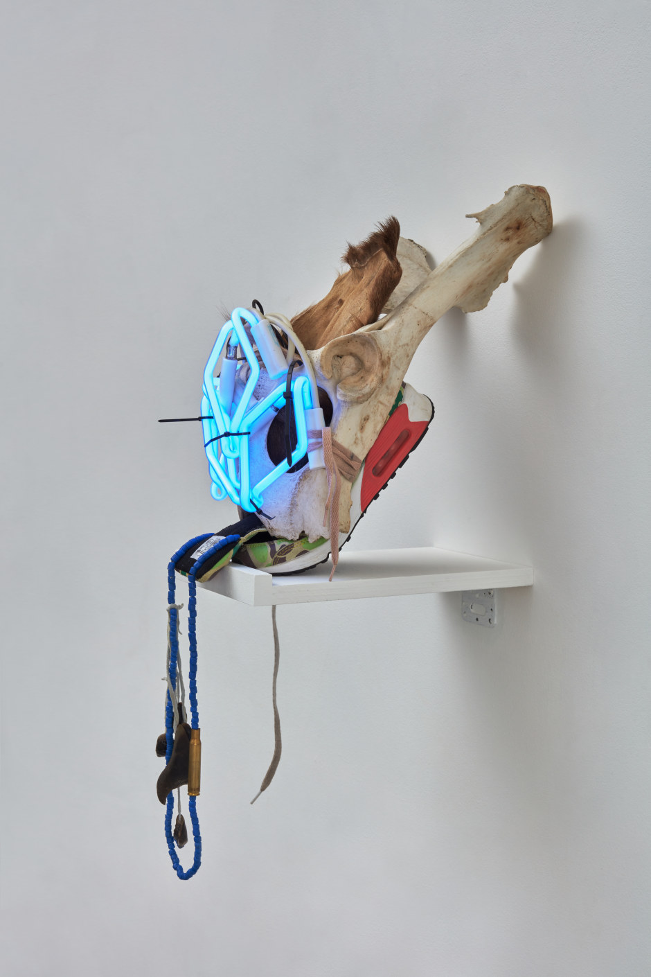 Natalie Ball  You usually bury the head in the woods Trophy Head, 2021  neon glass, extension cord, cow bone, shoe, deer hooves, beads, bullet case, elk hide  71 x 30.5 x 37 cm / 28 x 12 ⅛ x 14 ⅝ in