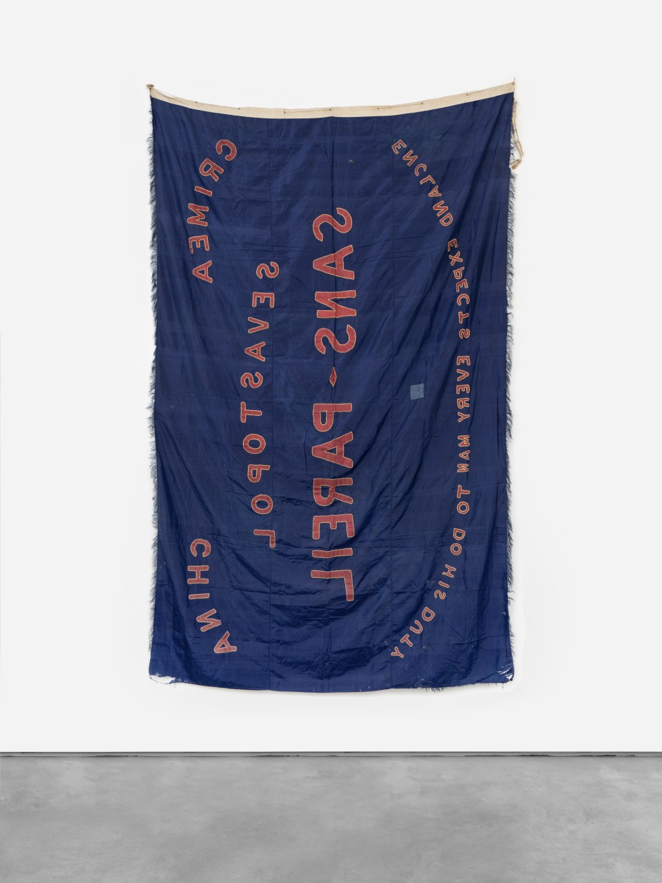 England Expects, circa 1857-1859  British naval celebration flag, double-sided silk appliqué with chain-stitch and applied fringe, cotton, twine with wooden toggle  152.5 x 250 x 0.5 cm / 60 x 98 ⅜ x ¼ in  Courtesy Simon Andrews and Sadie Coles HQ, London  Photo: Katie Morrison  21st October 1805 — an announcement of engagement, transmitted by semaphore flags from the masts of Nelson’s Victory to his assembled fleet, gathered in Cape Trafalgar to confront those of France and Spain, promises militant defiance and virtue in the face of opposition. England Expects Every Man To Do His Duty — a heroic mantra destined for resounding echo upon repeating daydreams of national identity, for Englishmen still yet to be born.   The flag was commissioned to celebrate homecoming, gallantly rigged below the Union Jack as officers and crew of HMS Sans Pareil returned to port and family after years of seafaring to the furthermost destinations of British imperial interest. Hand-stitched aboard ship from Chinese silk — that valuable asset of international trade — the sky-blue standard records the Black Sea engagements that preceded this, the second of the ship’s visits to China in 1857. Nelson’s charge emblazoned along, now manifesto for the Queen's Britain.   When the ship drew into Plymouth harbour in December 1859 she had for one year already been under the command of Captain Rochfort Maguire. No stranger to the globe’s oceans, Maguire’s prior commission had been to lead his survey cutter deep into the Arctic Circle. His mission then, as fruitless as all those before and those to come, to discover the fate of Sir John Franklin’s doomed odyssey, lost with all hands aboard Erebus & Terror. 