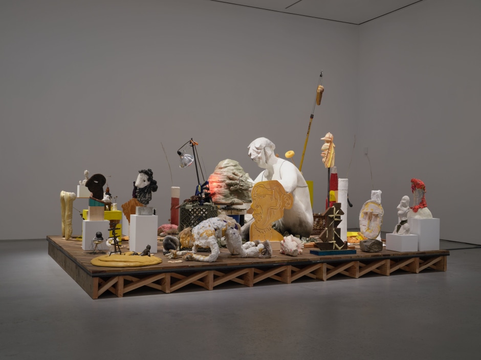 Nicole Eisenman  Maker's Muck  2022  Coney Island Boardwalk (Brazilian Ipe), plaster, bronze, silicone, unfired clay, fired clay, expanding foam, burlap, wire,  raw wool, sneakers, magic smooth, magic sculpt, resin, bamboo skewers, tin foil, plaster bandages, plywood, bass wood,  Aqua-Resin, fiberglass, seashell, styrofoam, oil paint, wax, carpet fringe, cardboard, cement, steel pipe, steel rod,  aluminum paint tubes, vinyl stickers, granite, telescopic extension pole, sand, fabric, crocheted rug, marbles,  miniature rocking chair, grass, woven rush stool, Formica, Le Beau Touché plasteline, canola oil, corn, Valvoline motor oil,  sponge, reflective fabric, nylon cord, charcoal, Shimpo Whisper pottery wheel, Saran wrap, coated wire, recording device,  AM/FM Radio, wood clamp, spring clamp, expansion clamp, heat lamp bulb, clip light, glass bottles, Plexiglas, dried flowers,  SLS plastic, dried plastic, milk crate, canvas, twine, copper tube, elastic cord, steel I-beam, MDF, iron object  261.62 x 304.8 x 393.7 cm x 103 x 120 x 155 in.