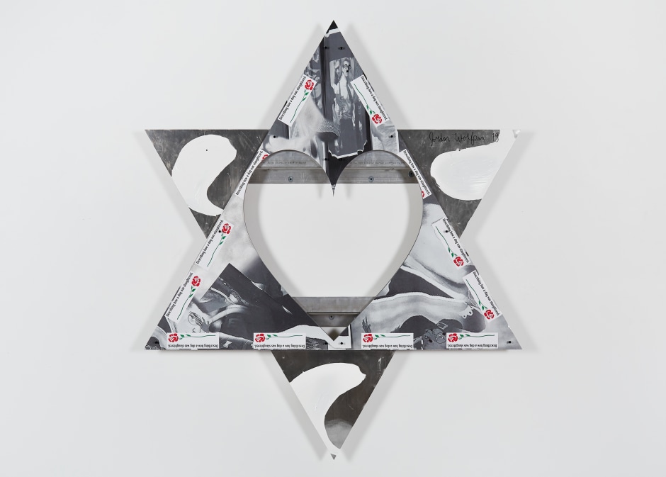 Jordan Wolfson  Untitled, 2019  UV print on aluminum with enamel paint, painted screws and bumper stickers  214 x 185.2 cm / 84 ¼ x 72 ⅞ in  In his aluminium panel from the series, all Untitled, 2019, Jordan Wolfson returns to the Star of David formation, appearing to gesture towards his own Jewish heritage, raising the question of how he fits into this constellation of American mythologies. The artist’s irreverent presence is felt in the various defacements of the collaged imagery, through digital warping, recurring bumper stickers and graffiti style moustaches, transforming JFK Jr., scion of an Irish Catholic dynasty, into a kind of Groucho Marx proxy. In this new iteration of the composition, Wolfson has punctured the central plane with a large heart, creating a negative void within the imagery and revealing the structure behind – again referencing the artist’s hand and control in the representation of the imagery. In every other pointed facet of the remaining surface, Kennedy Jr. is accompanied by a cartoonish, faced witch – simultaneously collaborator and product in the development of Wolfson’s practice. An allusion to the long history of witch representations, found in varying forms, and with various, developing roles, throughout the artist’s oeuvre: the murderous hag depicted in Riverboat song (2017), for example – a parallel to the wicked step-mother or governess, stepping in to intervene and discipline in often harrowing ways – or the ghoulish Halloween mask worn by Untitled (Female figure) (2014) – the dancing, animatronic figure violently spotlighting abject desires. Presented here in her interactions with Kennedy Jr., the familiar fairy-tale figure – at once comic and grotesque – embodies a duality prevalent throughout Wolfson’s work: the panels become double-edged entities of childish humour and innocence, and containers for darker thoughts, desires, or concerns.
