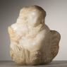 A figure of a crouching woman roughly hewn from a piece of alabaster
