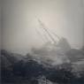 P photograph of a wrecked ship on a rocky outcropping in fog